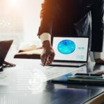 Geschäftsleute diskutieren Datenanalyse am Laptop | Pmcf